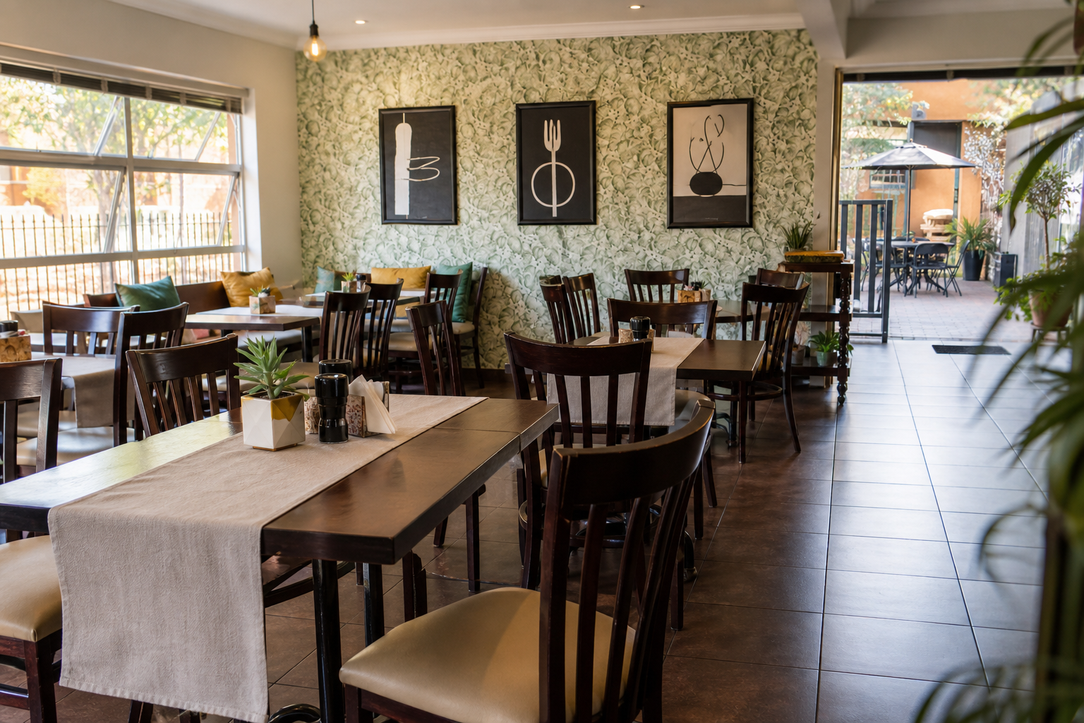 Bright dining room with dark wood tables and botanical wallpaper
